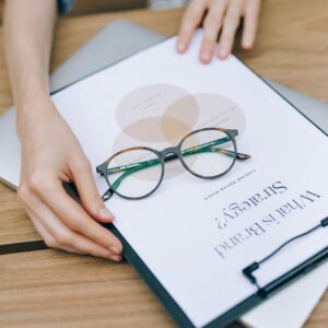 Close-up of eyeglasses on clipboard with brand strategy document, emphasizing business planning and analysis.